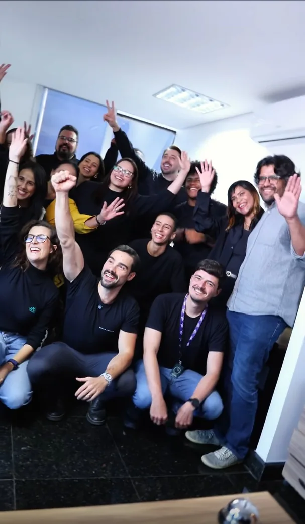 Equipe da Escalar reunida e sorrindo no escritório